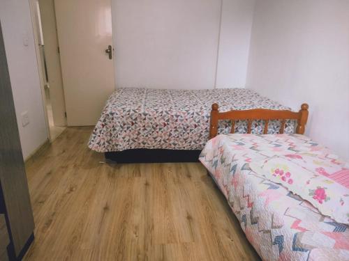 een slaapkamer met twee bedden en een houten vloer bij Apartamento 150m das Termas in Piratuba