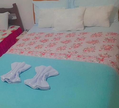 a bed with two pairs of slippers on top of it at Dormitório portal in Domingos Martins