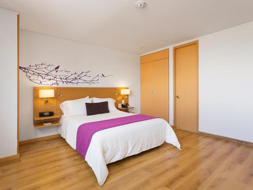 a bedroom with a large white bed and wooden floors at Hotel bh Parque 93 in Bogotá