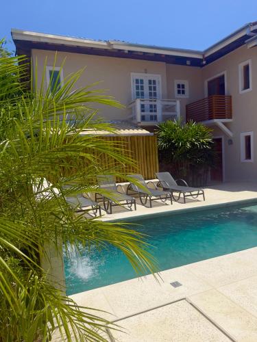 a swimming pool with chairs and a house at Pousada Pantai Maresias in Maresias