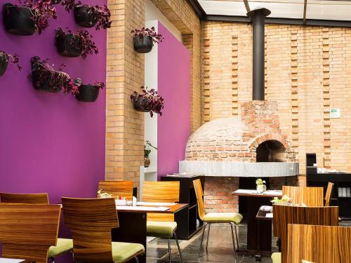 a restaurant with purple walls and a brick oven at Hotel bh Parque 93 in Bogotá