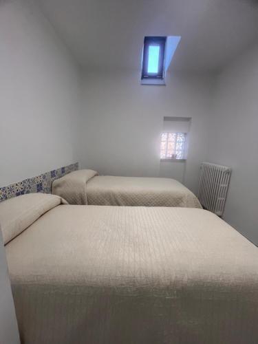 Twee bedden in een slaapkamer met een klein raam. bij Terrazza Appia 112 in Potenza