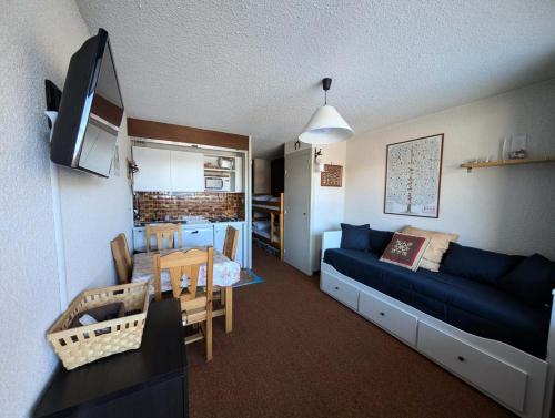 a living room with a blue couch and a kitchen at Résidence Chalmettes - Studio 2/4 personnes - Skis aux pieds MAE-9074 in Montgenèvre