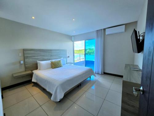 Un dormitorio con una cama con vista al mar. en Puerto Azul Hotel, en Puntarenas