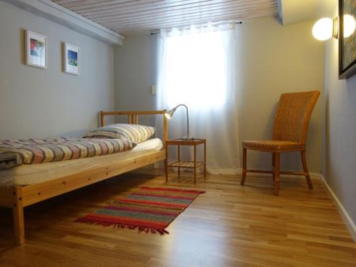 een slaapkamer met een bed, een stoel en een raam bij Gästehaus 1A in Lindlar