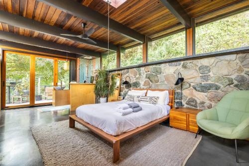 a bedroom with a bed and a stone wall at Two Creeks Treehouse in Mill Valley