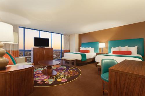 a hotel room with two beds and a flat screen tv at Masquerade Tower at Rio Hotel & Casino by Suiteness in Las Vegas