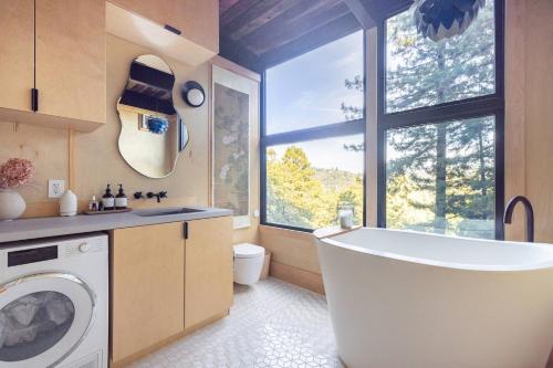 a bathroom with a tub and a washing machine at Two Creeks Treehouse in Mill Valley