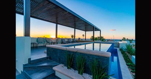 a house with a swimming pool with a sunset in the background at Santa Cruz Suites in La Paz