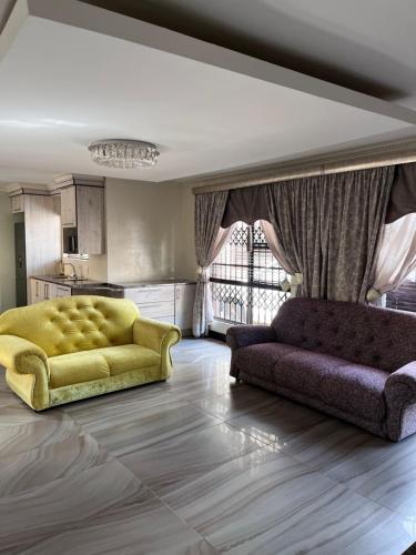 a living room with a yellow couch and a kitchen at Paradiso Palazzo in Welkom