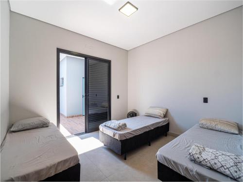een kamer met twee bedden en een raam bij Casa com Piscina, Wi-Fi e Garagem in Pirassununga