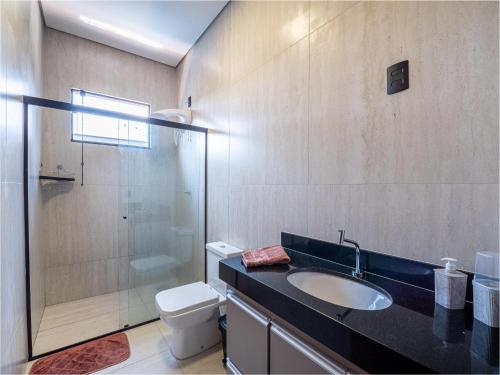 een badkamer met een wastafel, een toilet en een douche bij Casa com Piscina, Wi-Fi e Garagem in Pirassununga