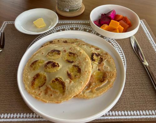 un piatto di cibo con pancake e una ciotola di frutta di Balian River Hut a Balian