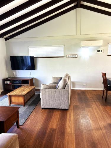 a living room with a couch and a tv at Stouty's at Hat Head - No Sheets or Towels Provided in Hat Head