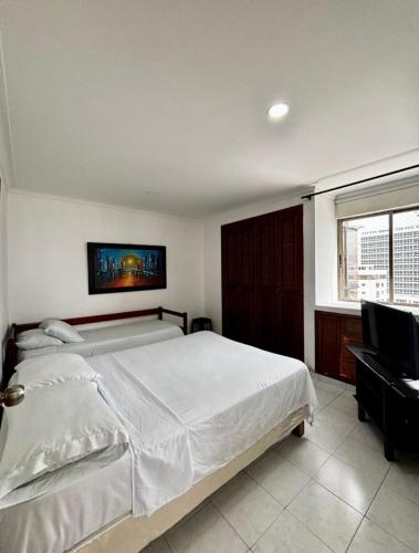 a bedroom with a large white bed and a window at Paraíso en Bocagrande Apartaestudio in Estación El Salto