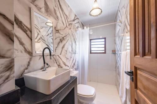 a white bathroom with a sink and a toilet at Pousada Arraial dos Sonhos in Arraial d'Ajuda