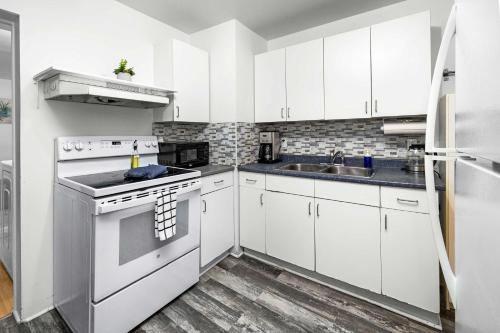 a white kitchen with a stove and a sink at Urban 3BR Getaway Walk to ByWard Market- UOttawa in Ottawa