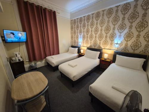 a hotel room with two beds and a table at Victorin House - All rooms are EN-SUITE in Portsmouth