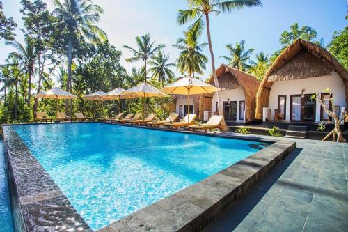 a pool at a villa with chairs and umbrellas at Bintang Bungalow in Nusa Penida