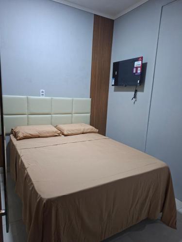 a bedroom with a bed with a tv on the wall at Espaço completo aconchegante no 2 andar in Belém