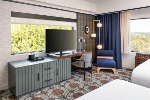 a hotel room with a desk and a tv at The Mecklen Hotel, Charlotte, a Tribute Portfolio Hotel in Charlotte