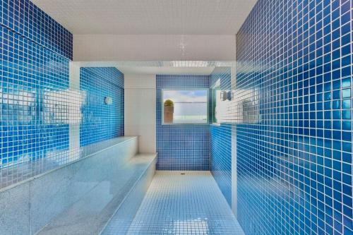 ein Badezimmer mit blau gefliesten Wänden und einer Dusche in der Unterkunft 16º andar com vista pro mar in Macaé