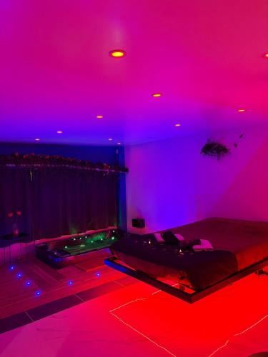 a room with a bed with red and blue lights at Love 2 avec Jacuzzi in Cap d'Agde
