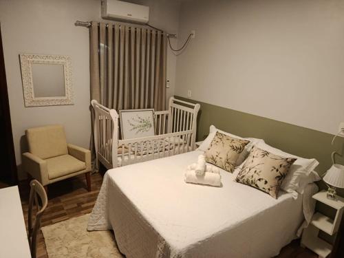 a bedroom with a bed with a crib and a chair at Vinhas das Grutas in Soledade