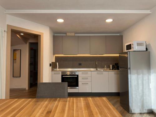 une cuisine avec des armoires blanches et un réfrigérateur en acier inoxydable dans l'établissement Appartamenti LITEGOSA casa vacanza 3, à Panchià