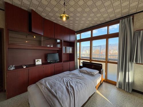 ein Schlafzimmer mit einem großen Bett und einem Fernseher in der Unterkunft 三ツ和のお宿 in Nakano