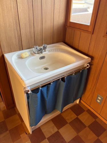 a bathroom sink with blue towels under it at 三ツ和のお宿 in Nakano