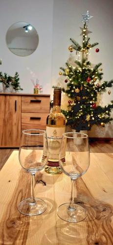 eine Flasche Wein und zwei Gläser auf einem Tisch mit einem Weihnachtsbaum in der Unterkunft Apartament dzika róża in Kowary