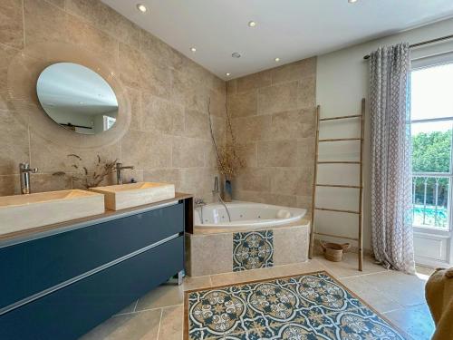 ein Badezimmer mit Badewanne, Waschbecken und Spiegel in der Unterkunft Modern Provençal Villa At The Forest's Edge in Le Tignet