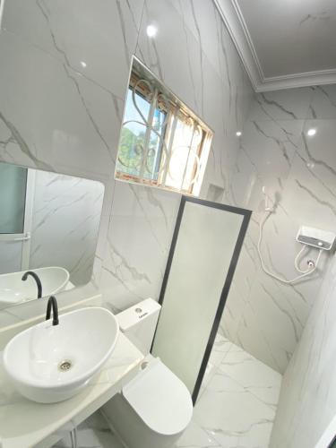 a white bathroom with a sink and a mirror at HalmaHome Two Bedroom Apartment in Zanzibar City