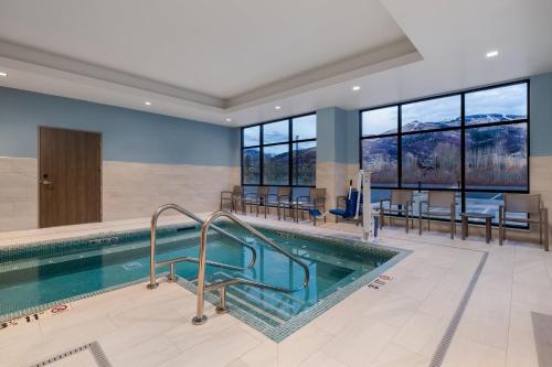 a swimming pool in a hotel with tables and chairs at Holiday Inn Express & Suites Steamboat Springs by IHG in Steamboat Springs