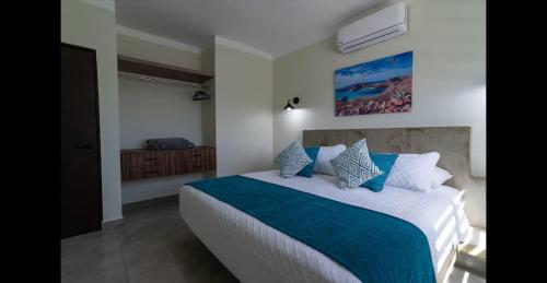 ein Schlafzimmer mit einem großen Bett mit blauen und weißen Kissen in der Unterkunft Santa Cruz Suites in La Paz