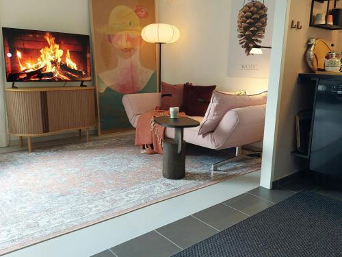 Una sala de estar con chimenea y una mesa. en Retro Guest House Near Rebild Hills, en Hadsund