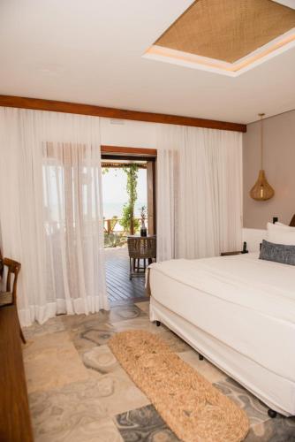 a bedroom with a large white bed and a window at Carlore Hotel Taíba in Taíba