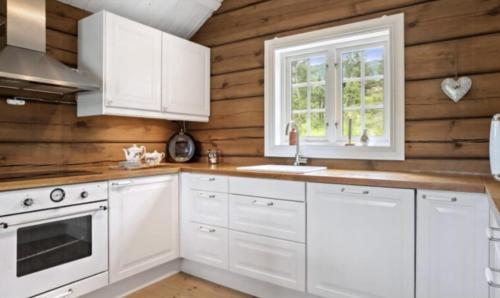 una cucina con armadietti bianchi e pareti in legno di Timber Cabin With Soul At Kvamskogen a Norheimsund