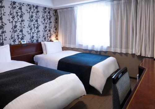 a hotel room with two beds and a window at APA Hotel Haneda Anamori Inari Ekimae in Tokyo