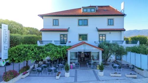 a large white building with tables and chairs at Hotel O Encontro in Sendim