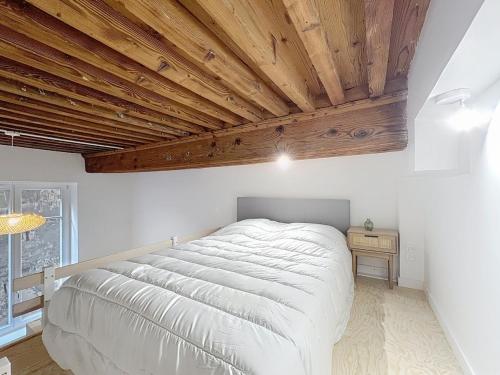 un grande letto in una camera da letto con soffitti in legno di Le BEAU LOUIS a Lione