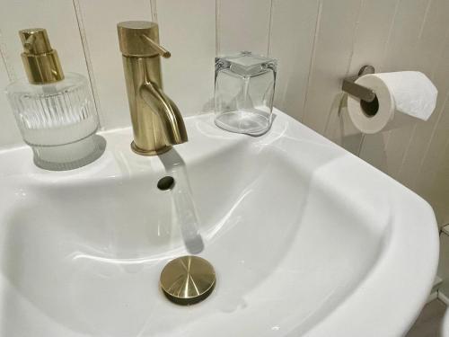 a bathroom sink with a gold faucet and a glass at Trinity House Hotel in London