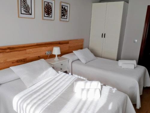 twee bedden in een kamer met witte lakens bij La Esperanza in Teruel