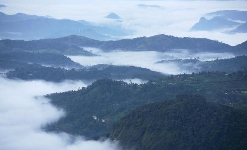 a view of a mountain valley with clouds and fog at Windermere Estate in Munnar