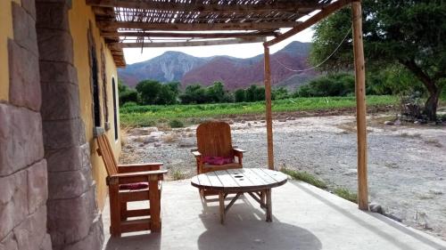 a table and a chair on a porch with a view of mountains at Nativas Cabaña Amarilla in Senador Pérez