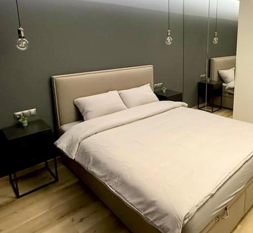 een slaapkamer met een groot wit bed en 2 tafels bij Apartament Jurowiecka 17 in Białystok