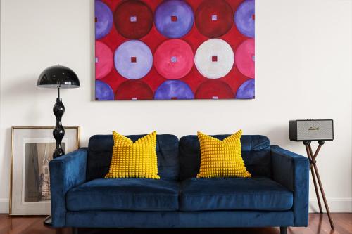 a blue couch with yellow pillows in a living room at Artistic Opera House Retreat - Entire Apartment - 5-Min Ferry to CBD in Sydney