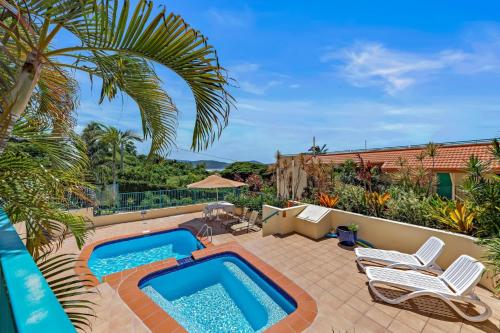 a patio with a swimming pool and chairs and a house at Shingley Beach Retreat - Ocean Views Apartment in Airlie Beach