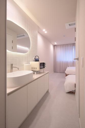 a white bathroom with a sink and a bed at Stay BUT SEONGSU in Seoul
